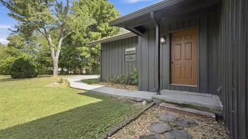 A residential building with a front door, a pathway leading to the entrance, and a well-maintained lawn.