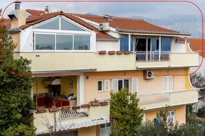 Een gebouw met twee verdiepingen, een balkon, een schotelantenne en een schoorsteen.