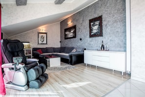 A modern living room with a grey sofa, a massage chair, a white cabinet, and framed artwork on the walls. - Luxury spacious apartment close to Znjan beach with the sea view (Split)