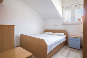 A bedroom with a wooden bed, a small bedside table, a nightstand, and a window with blinds. - Luxury spacious apartment close to Znjan beach with the sea view (Split)