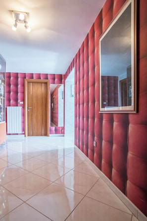 Ein Flur mit Holztür, großem Spiegel und einer gepolsterten Wand in Rot.