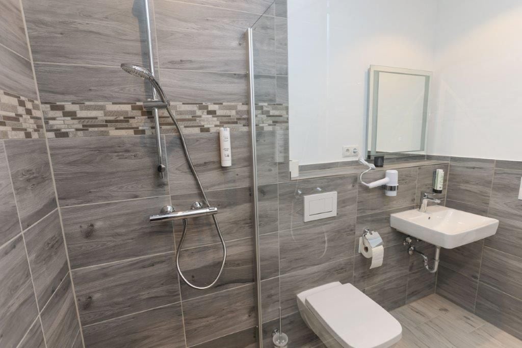 Ein modernes Badezimmer mit einer gläsernen Dusche, einem weißen Waschbecken und einer Toilette.