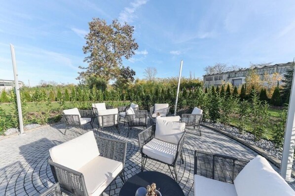 An outdoor seating area with wicker furniture and a view of a landscaped garden.