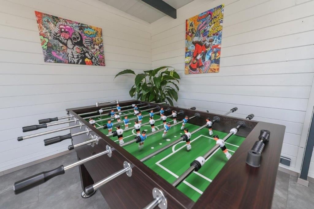 Ein Fußballtisch in einem Raum mit weißen Wänden und zwei farbenfrohen Bildern.