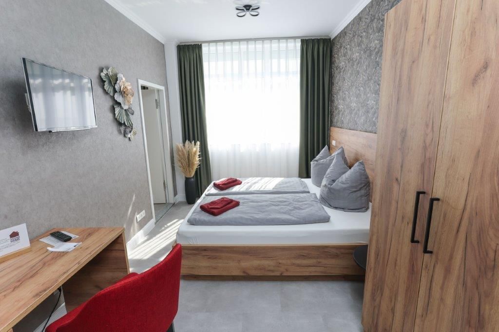 Een moderne hotelkamer met een bed, een bureau, een televisie en een kledingkast.