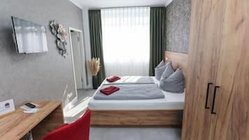 Een moderne hotelkamer met een bed, een bureau, een televisie en een kledingkast.