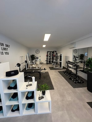 A gym with exercise equipment, a mirror, and a motivational quote on the wall.