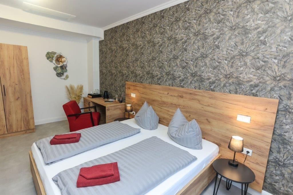 Ein Hotelzimmer mit einem Doppelbett, einem Schreibtisch, einem Stuhl und einem Kleiderschrank.