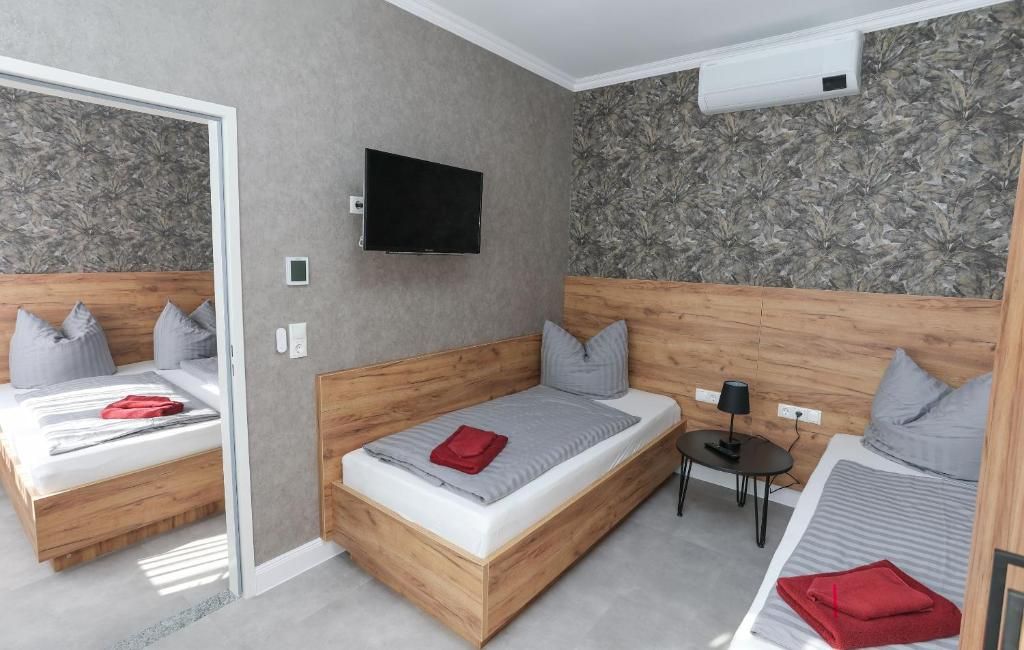 Moderni hotellihuone, jossa on kaksi sänkyä, taulutelevisio ja pieni pöytä.