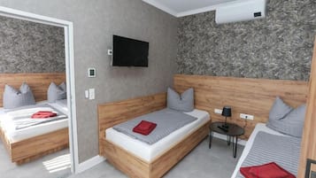 Moderni hotellihuone, jossa on kaksi sänkyä, taulutelevisio ja pieni pöytä.