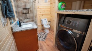 Een kleine badkamer met een wastafel, toilet en wasmachine.