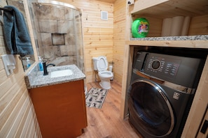 A compact bathroom with a sink, toilet, and washing machine. - Cozy 2-bedroom cabin with AC in Jacksonville, Alabama (Jacksonville)