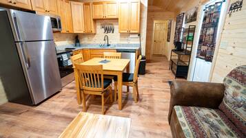 A compact kitchen with wooden cabinets, a stainless steel refrigerator, a microwave, and a coffee machine.