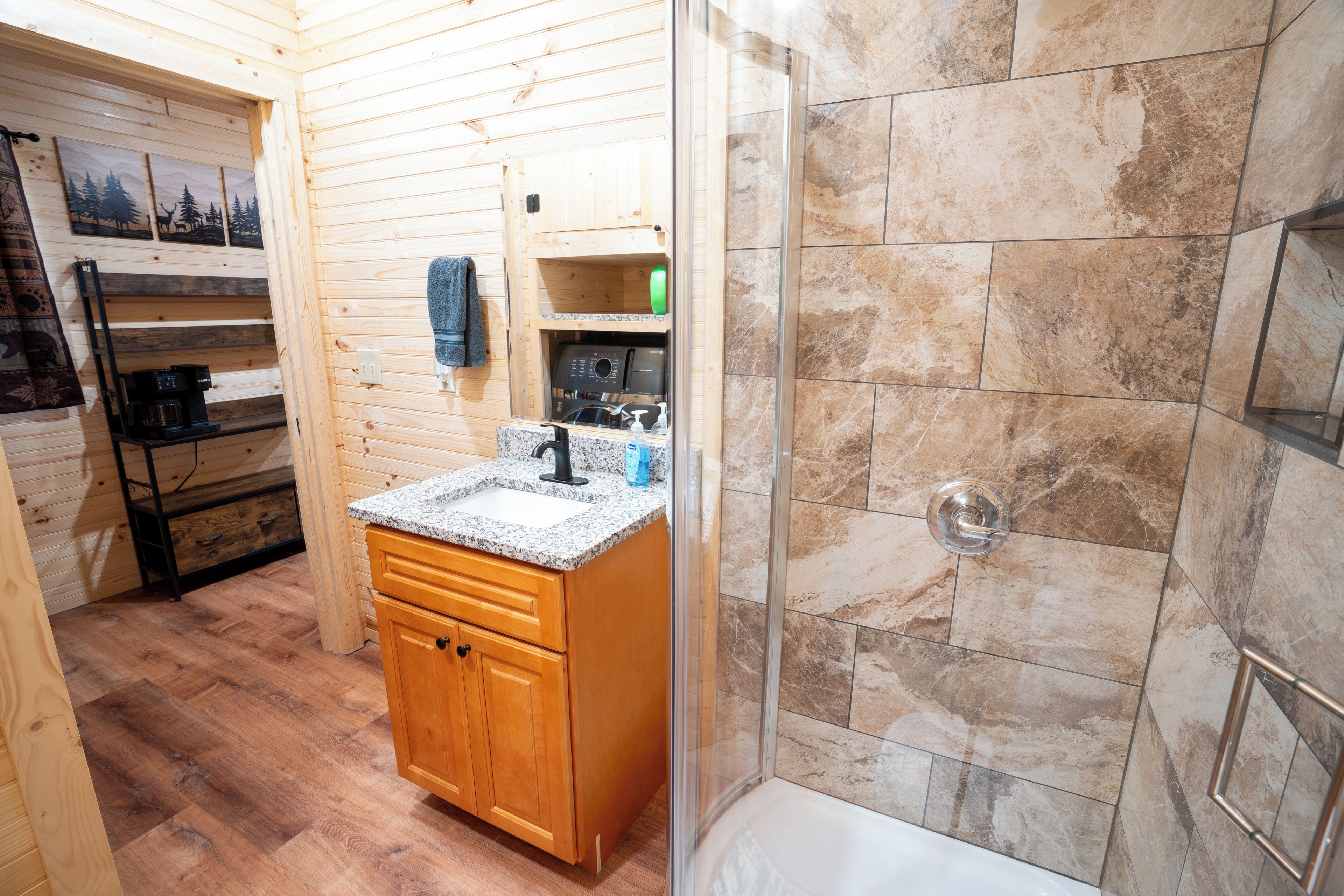 A bathroom with a shower, a sink, and wooden cabinetry.