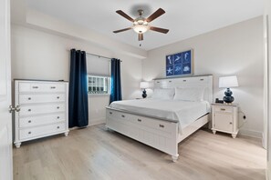 A bedroom with a bed, dresser, nightstand, and a ceiling fan. - Sea Glass 411 (Gulf Shores)