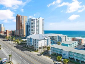 A coastal cityscape with modern buildings, a clear sky, and a view of the ocean. - Sea Glass 411 (Gulf Shores)