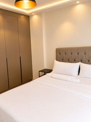 A hotel room with a large bed, a wardrobe, and a bedside table. - Modern 1BR SouthPark Near JKIA (Nairobi)