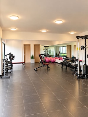 A spacious gym with various exercise equipment, a large mirror, and a clean, modern design. - Modern 1BR SouthPark Near JKIA (Nairobi)