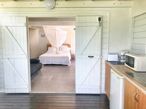 Un dormitorio con cama, mesita de noche y velador. Hay un dosel blanco sobre la cama.