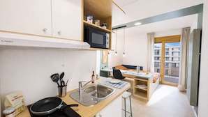 Une petite cuisine équipée d’un four à micro-ondes, d’un évier et d’une cuisinière.