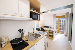 A compact kitchenette with a microwave, a sink, and a stove. - Kley Paris-Saint-Ouen (Saint-Ouen-sur-Seine)