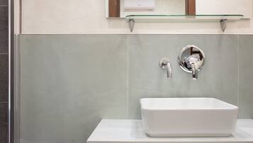 Ein Badezimmer mit einem weißen Waschbecken, einer Glasablage darüber und einem Spiegel mit Holzrahmen.