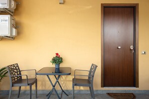 A room with a wooden door, a small table with two chairs, and a potted plant.