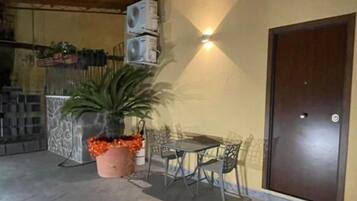 Ein Terrassenbereich im Freien mit Tisch, Stühlen, einem Blumentopf und einer Tür.