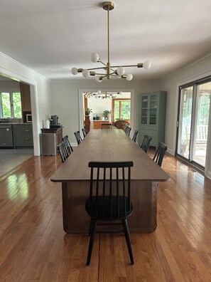 A spacious dining area with a long wooden table, black chairs, and a modern chandelier. - Pen y Bryn - 5BR Blue Ridge Luxury Retreat with Pool, Library & Game Room (Faber)