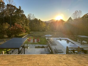 A pool area with lounge chairs and a deck overlooking a landscaped garden.