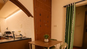 A compact kitchen with a wooden table and chairs, a bench, and a clock on the wall. - 2bhk Malleswaram templeview-veg only (Bengaluru)