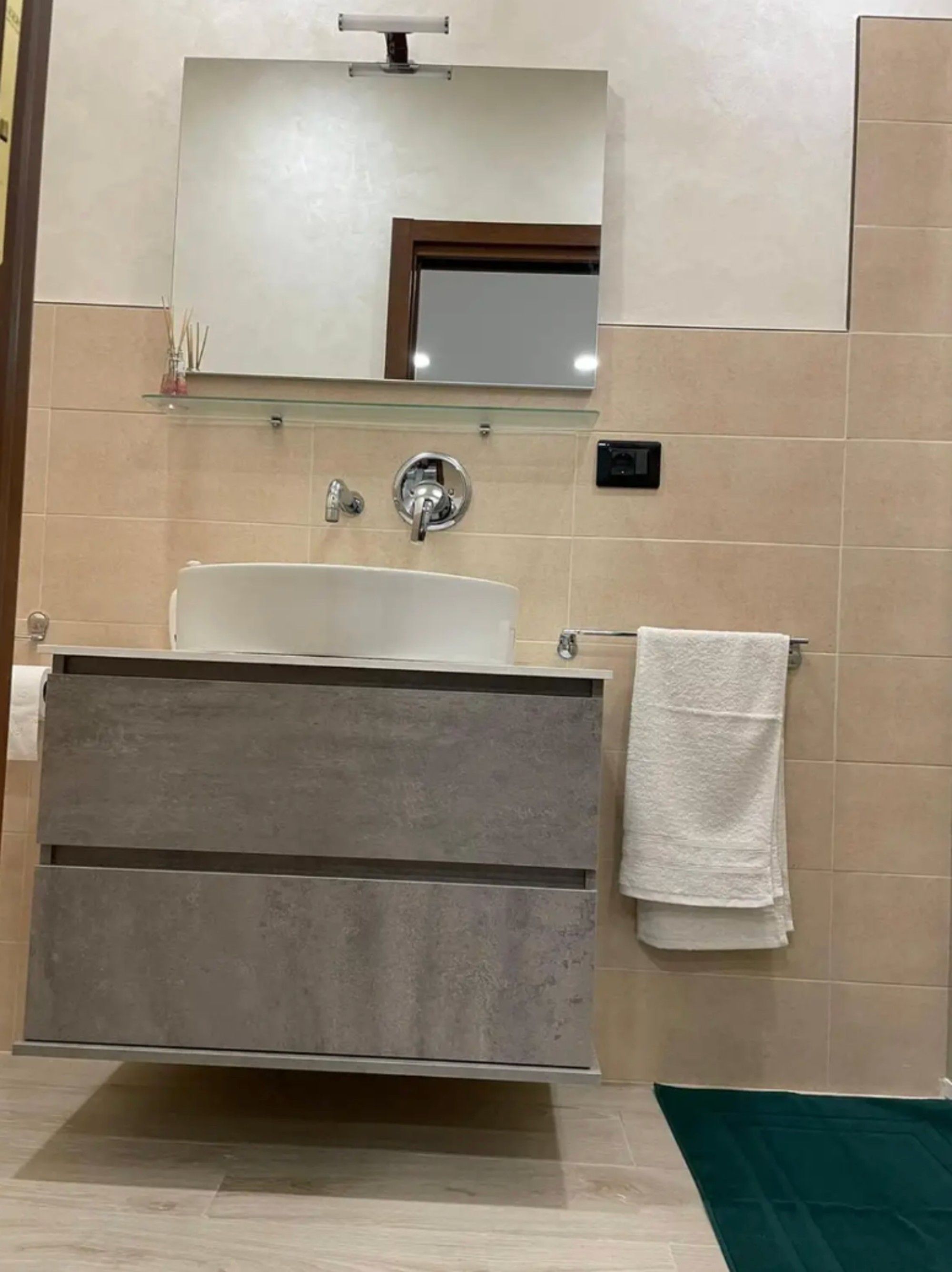 Ein Badezimmer mit einem weißen Waschbecken, einem Spiegel darüber und einem Handtuch an der Wand.