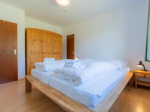 A hotel room with a large bed, wooden wardrobe, and a bedside table with a lamp. - Holiday Apartment With 2 Bedrooms (St. Peter-Ording)