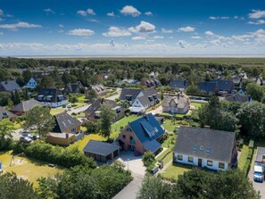A residential area with houses, some with sloped roofs and others with flat roofs, surrounded by greenery and a clear sky. - Holiday Apartment With 2 Bedrooms (St. Peter-Ording)