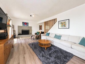 Ein modernes Wohnzimmer mit Kamin, einer Sofagarnitur, einem Couchtisch und einem Fernseher.