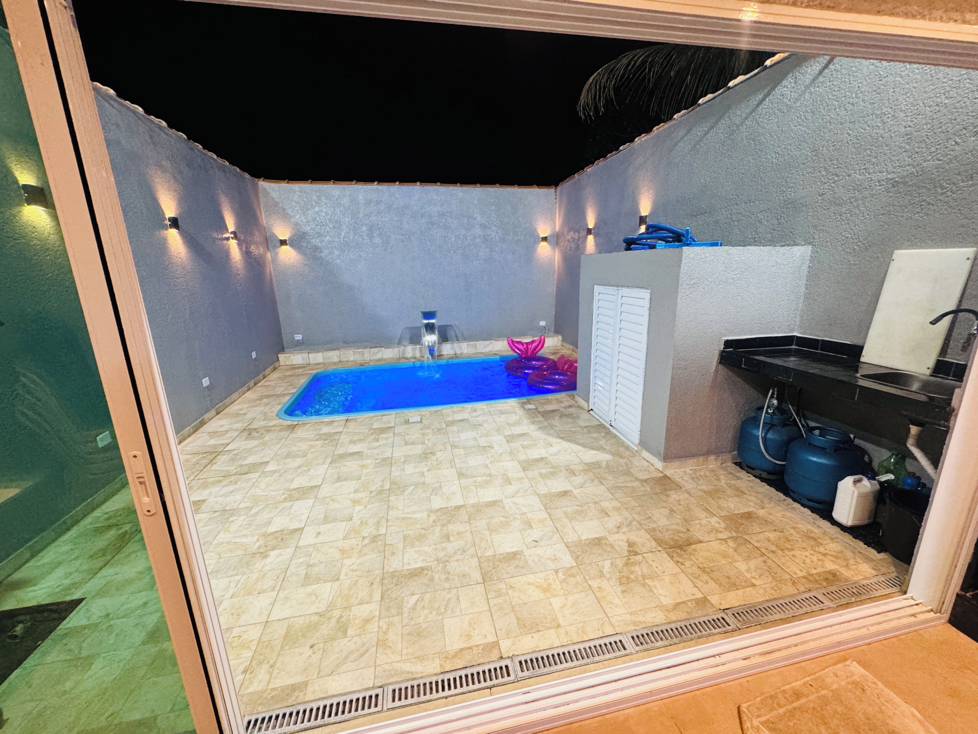 Un área de piscina pequeña y privada con suelo de baldosas, una fuente y un lavabo.
