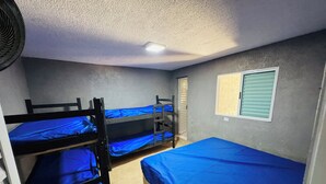 A dormitory room with bunk beds, a window with blinds, and a ceiling fan. - Perfect com piscina e 3-bedroom house in Peruíbe for a relaxing getaway (Peruíbe)
