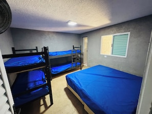 A dormitory room with bunk beds, a window with blinds, and a ceiling fan. - Perfect com piscina e 3-bedroom house in Peruíbe for a relaxing getaway (Peruíbe)