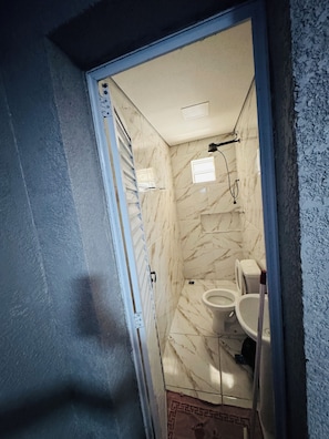 A bathroom with a toilet, a sink, and a shower area. - Perfect com piscina e 3-bedroom house in Peruíbe for a relaxing getaway (Peruíbe)