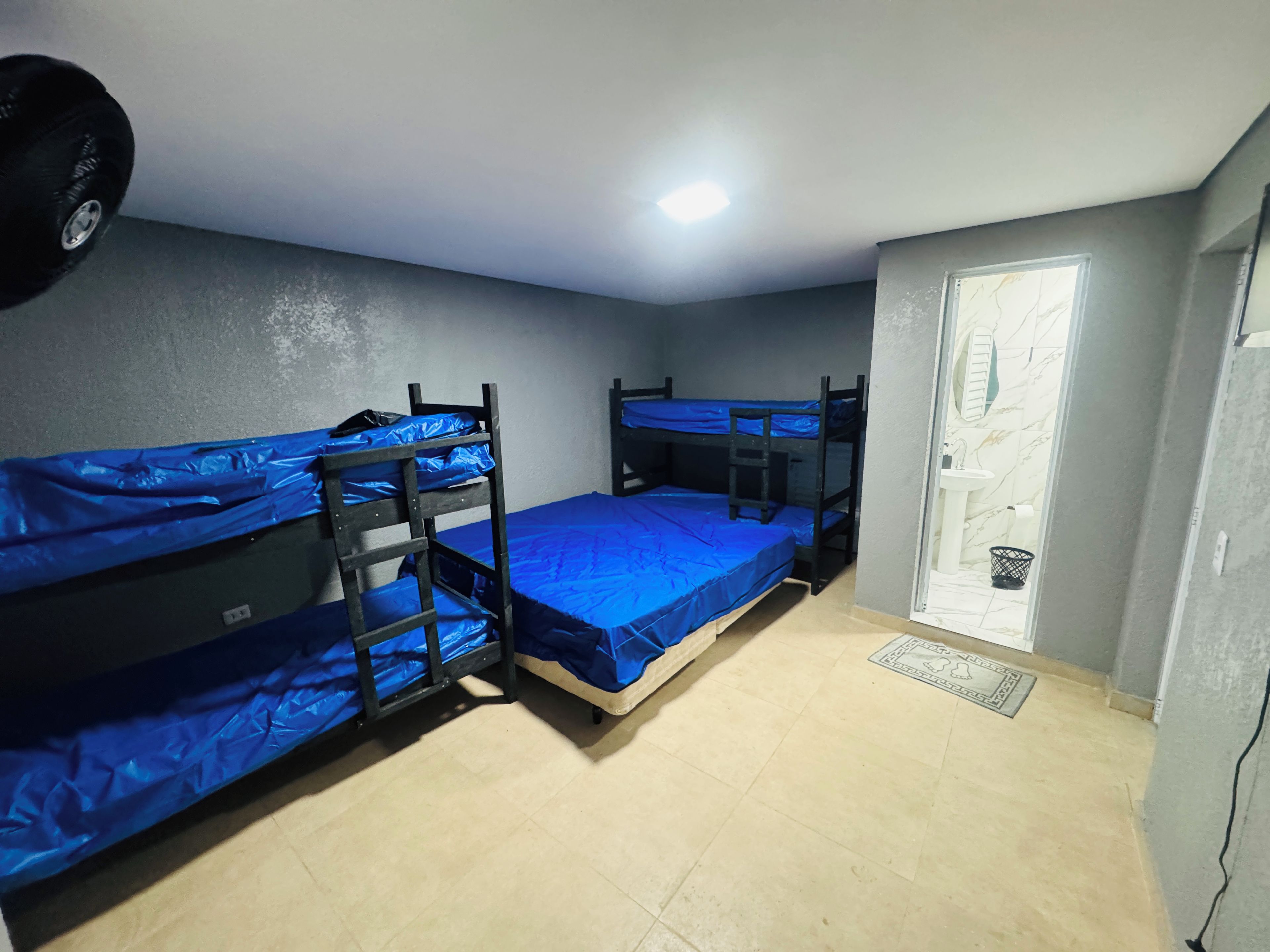 A room with three bunk beds, a white sink, and a door leading to a bathroom.
