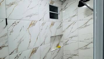 A bathroom with a toilet, a shower area, and a small window.