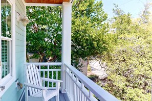 A porch with a white railing, a white chair, and a view of trees and foliage. - Stunning Intracoastal Views + Sunset Porch | Easy Beach Access | 5BR | Sleeps 12 (Wrightsville Beach)