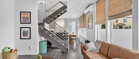 A modern living room with a staircase, a sofa, a coffee table, and framed pictures on the wall.