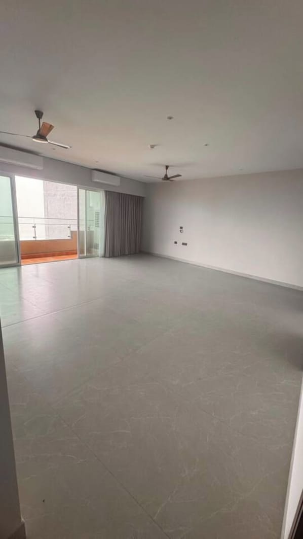 A spacious room with a large open area, a ceiling fan, and a sliding glass door leading to an outdoor balcony. - Magnolia View Retreat | Rooftop Deck + Parking (Seattle)