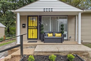 A house with a yellow door, a mailbox, and a welcome mat. - The Hidden Gem : A Bold 4BR Home w/ Game Room + Movie Lounge (St. Louis)