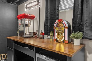 Ein Zimmer mit Schreibtisch aus Holz, einer Popcornmaschine, einer Jukebox und einem Topfpflanzen.
