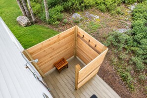 Una estructura de sauna de madera con bancos y un grifo metálico en una terraza.