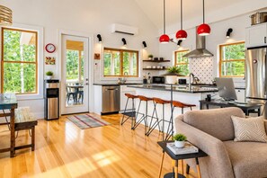 A modern kitchen with a central island, bar stools, and a dining area with a wooden table and chairs.