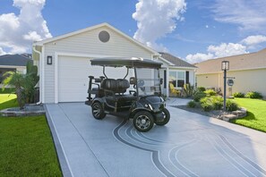 Ein Golfmobil steht auf einer Auffahrt, im Hintergrund ist ein Haus zu sehen.