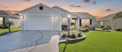 A residential house with a garage, a well-maintained lawn, and a driveway.